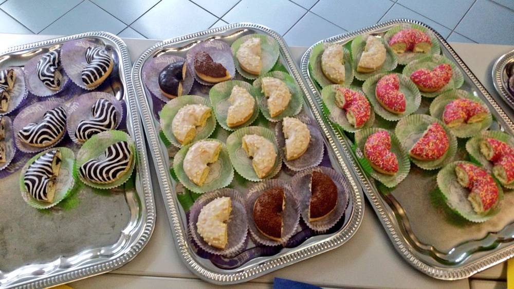 Trays of frosted donuts and pastries with zebra and pink sprinkle patterns.