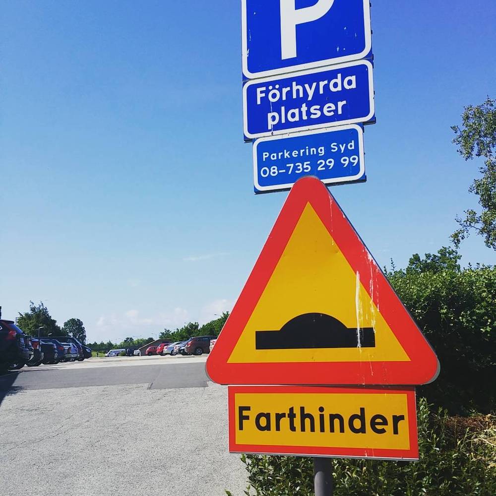 A Swedish speed bump warning sign reading 'Farthinder' beside a 'Förhyrda platser' parking sign.