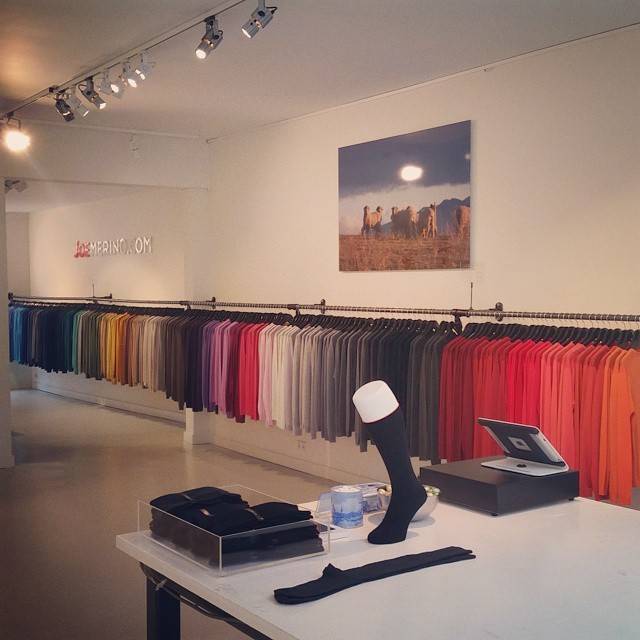 A clothing showroom with racks of colorful garments and a single sock displayed on a pedestal.