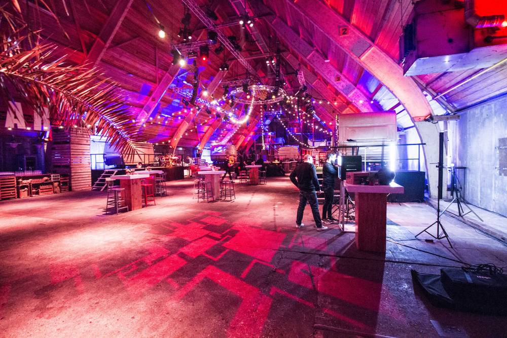 Guests set up high tables in the red and blue-lit lounge hall at De Fabrique.