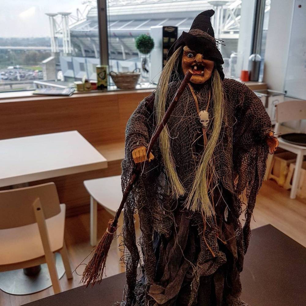 A Halloween witch decoration standing in an office break area.