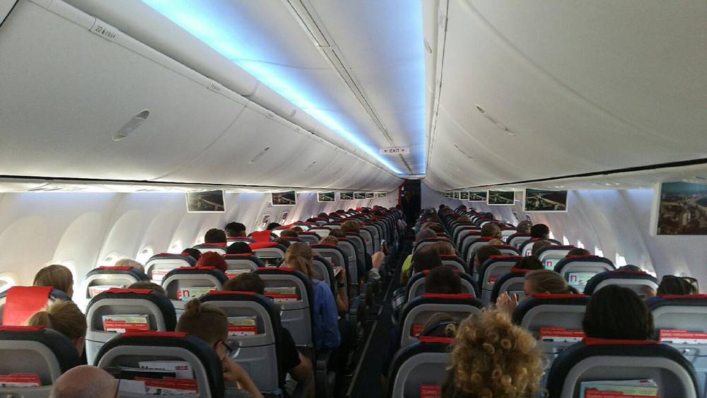 The interior of an airplane cabin filled with seated passengers during boarding.