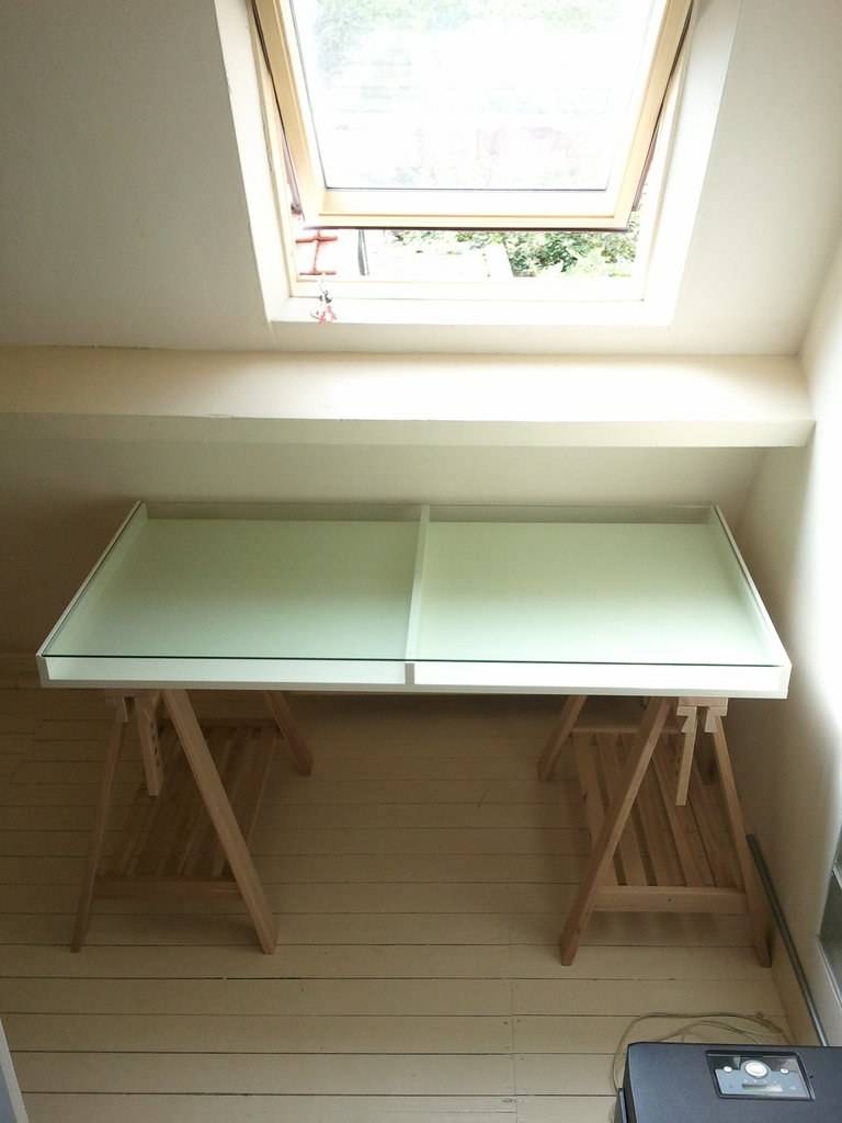 A newly assembled desk sits beneath a skylight in an attic room.
