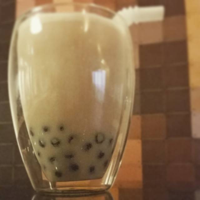 A glass of bubble tea with tapioca pearls settled at the bottom.