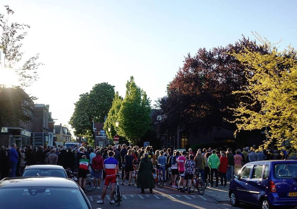 A crowd gathered on a tree-lined street at sunset.