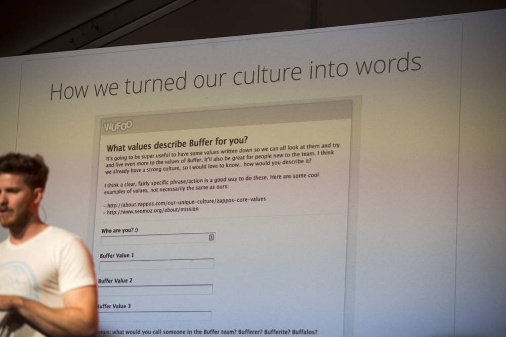 A speaker gestures beside a slide asking 'What values describe Buffer for you?'.