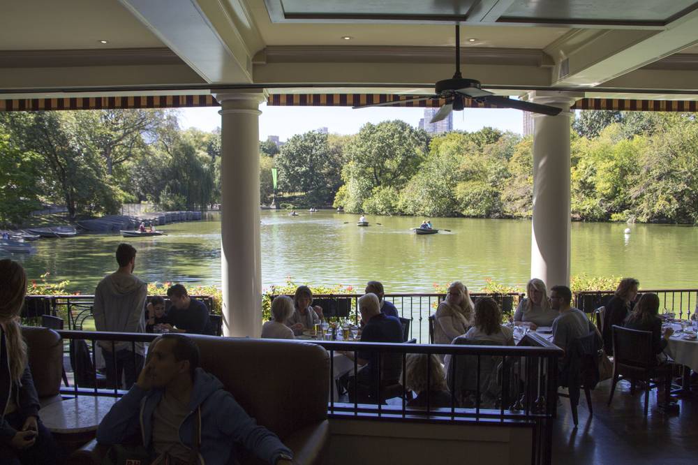Diners relax under a covered terrace overlooking the Central Park boating lake.
