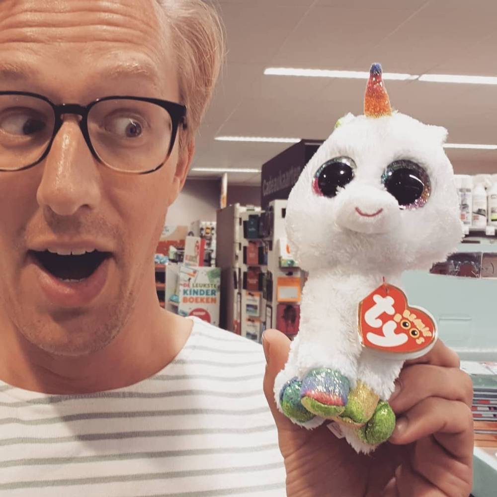Selfie holding a plush unicorn toy in a shop.