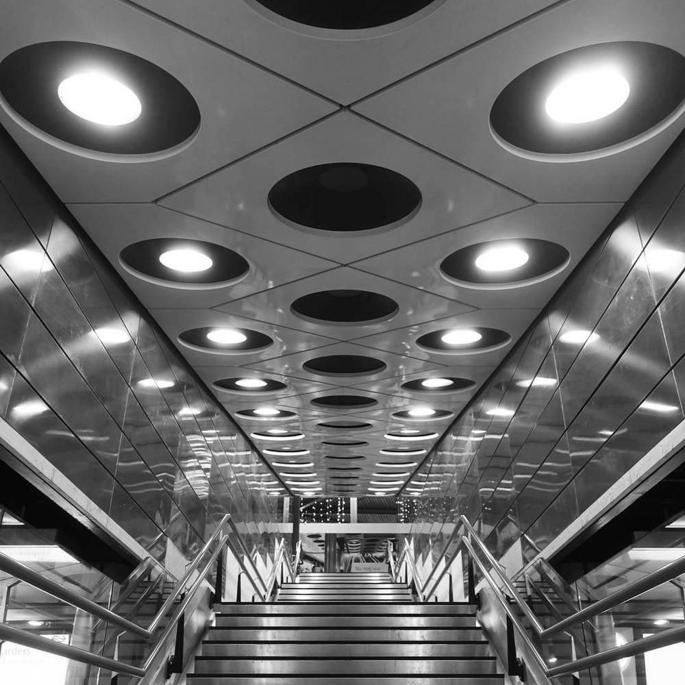 Black and white photo of a stairwell with round recessed ceiling lights.