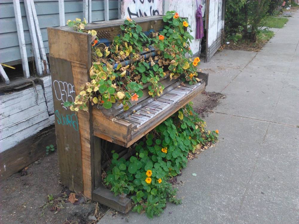 sidewalk piano with plants growing out of it