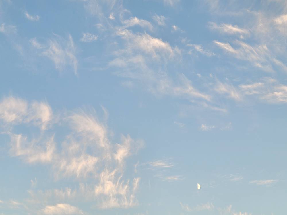blue sky with wispy clouds and half moon