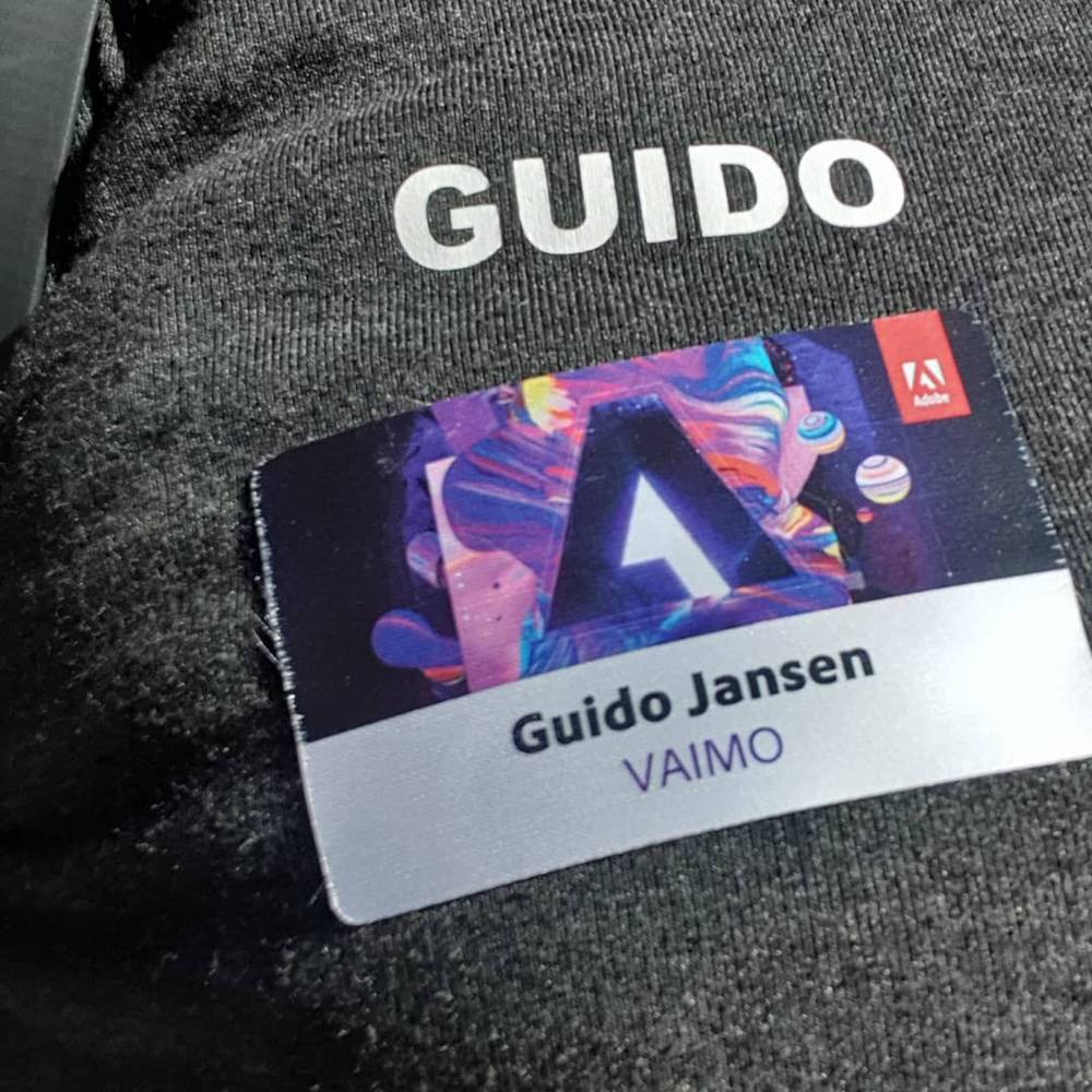Close-up of a grey hoodie printed with "Guido" and an Adobe conference badge clipped to it.