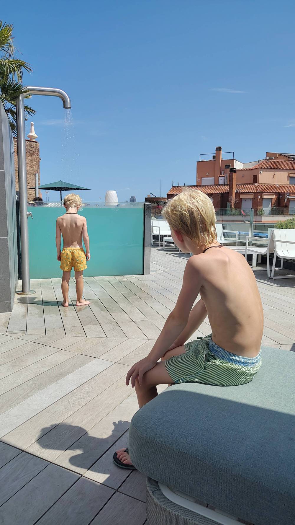Two boys sit by a rooftop pool overlooking the town.