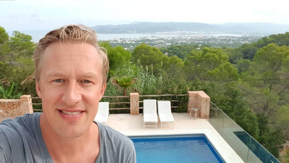 Selfie by a pool overlooking a forested hillside and distant town.