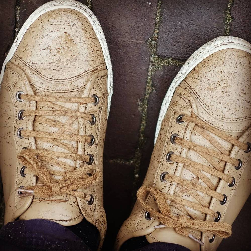 A pair of dirty white sneakers on wet pavement.