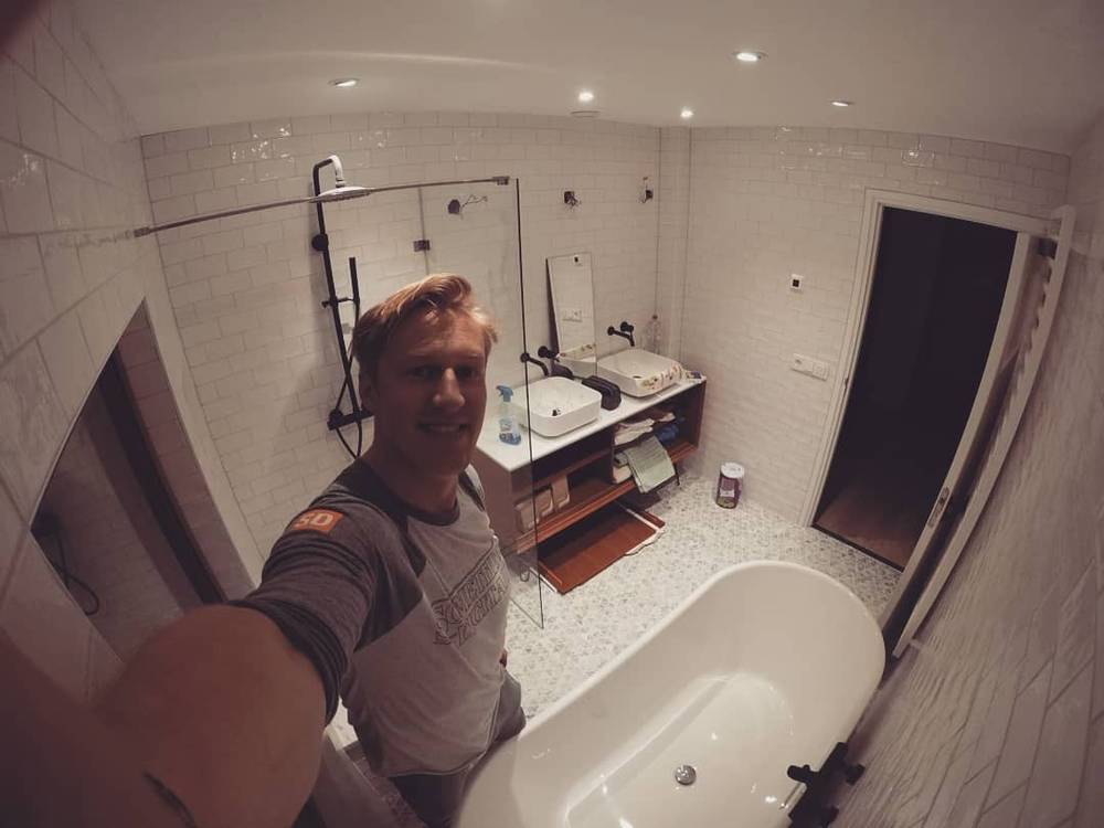 Selfie in a modern bathroom with a freestanding tub and glass shower.