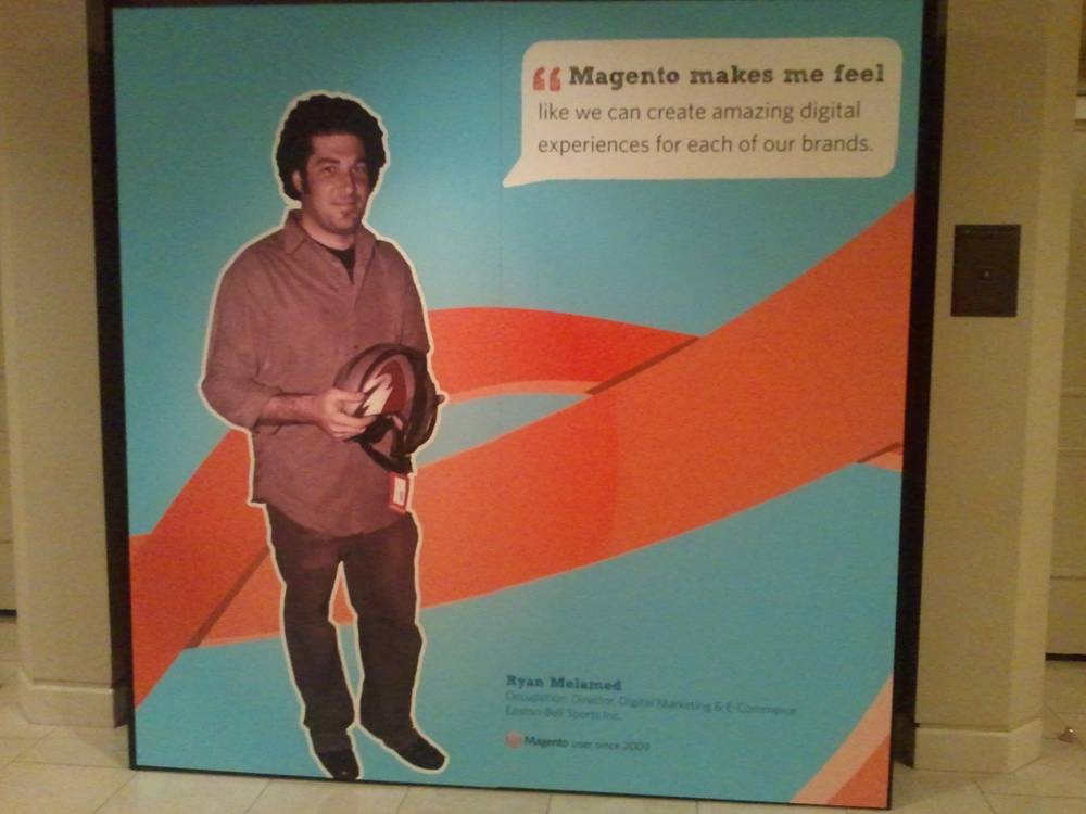 A life-size cutout of a man stands beside a quote reading 'Magento makes me feel like we can create amazing digital experiences.'
