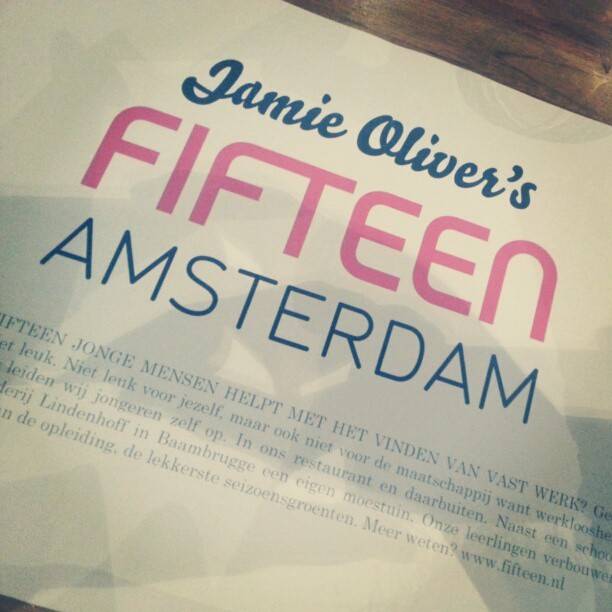 A restaurant sign reading 'Jamie Oliver's Fifteen Amsterdam' with descriptive text about the social enterprise restaurant.