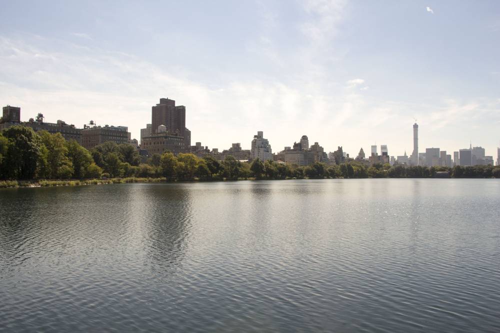 The Manhattan skyline rises beyond the calm Central Park reservoir.
