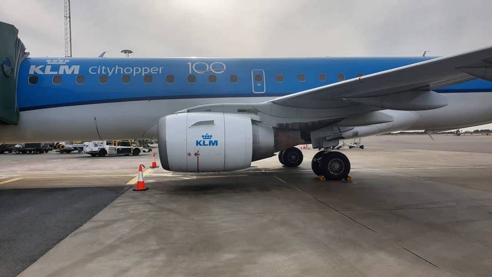 An airplane wing with KLM Cityhopper livery is parked at an airport.