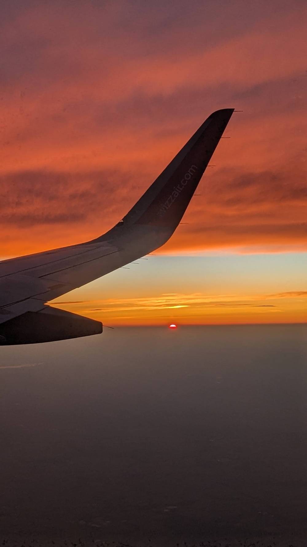 An airliner wing seen from the window at sunset