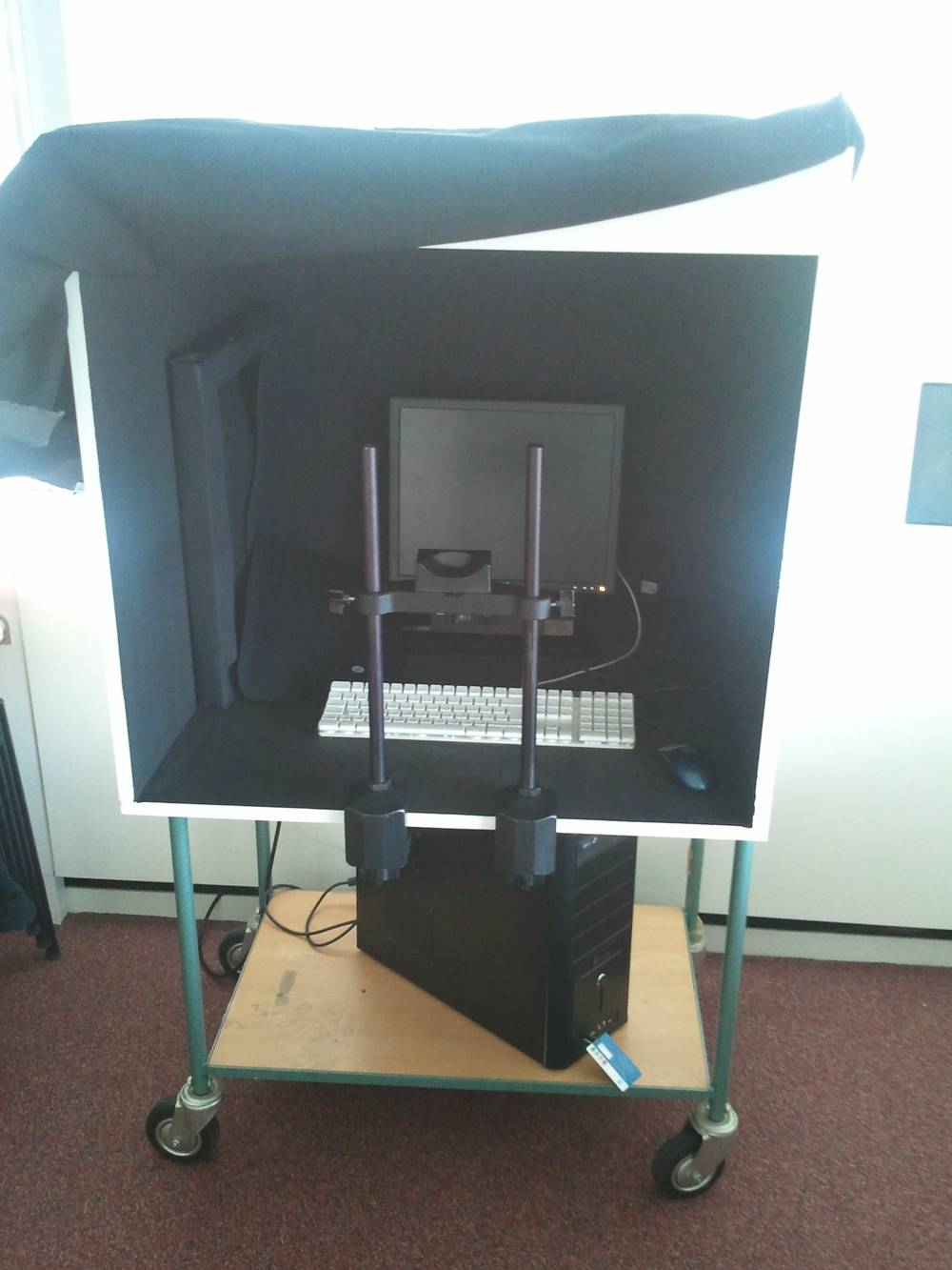 A wheeled cart holds a mobile eye-tracking setup with a monitor and camera rig.