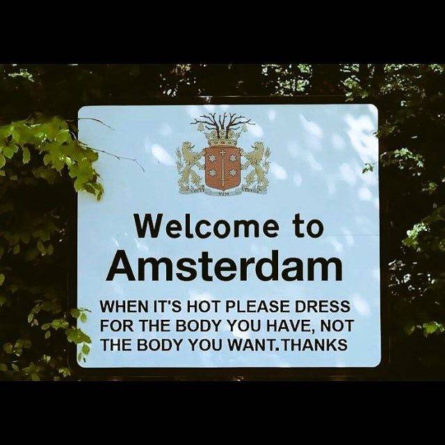 A humorous sign in Amsterdam reading "Welcome to Amsterdam. When it's hot please dress for the body you have, not the body you want. Thanks."