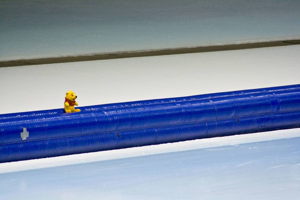A small stuffed Winnie the Pooh toy sits perched on the rink's blue barrier.