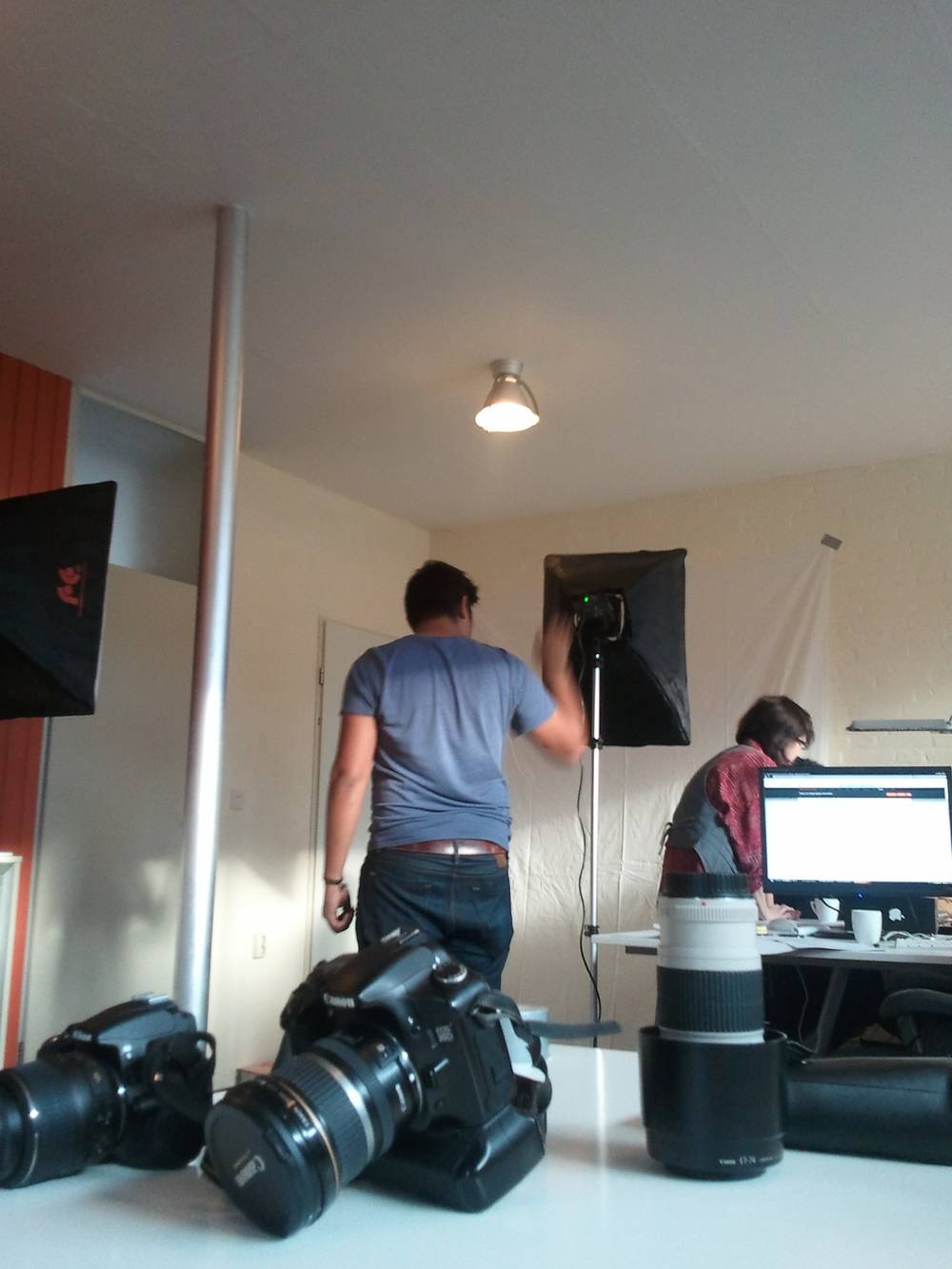 Two people set up studio lighting and cameras for a photoshoot at the Realvine office.