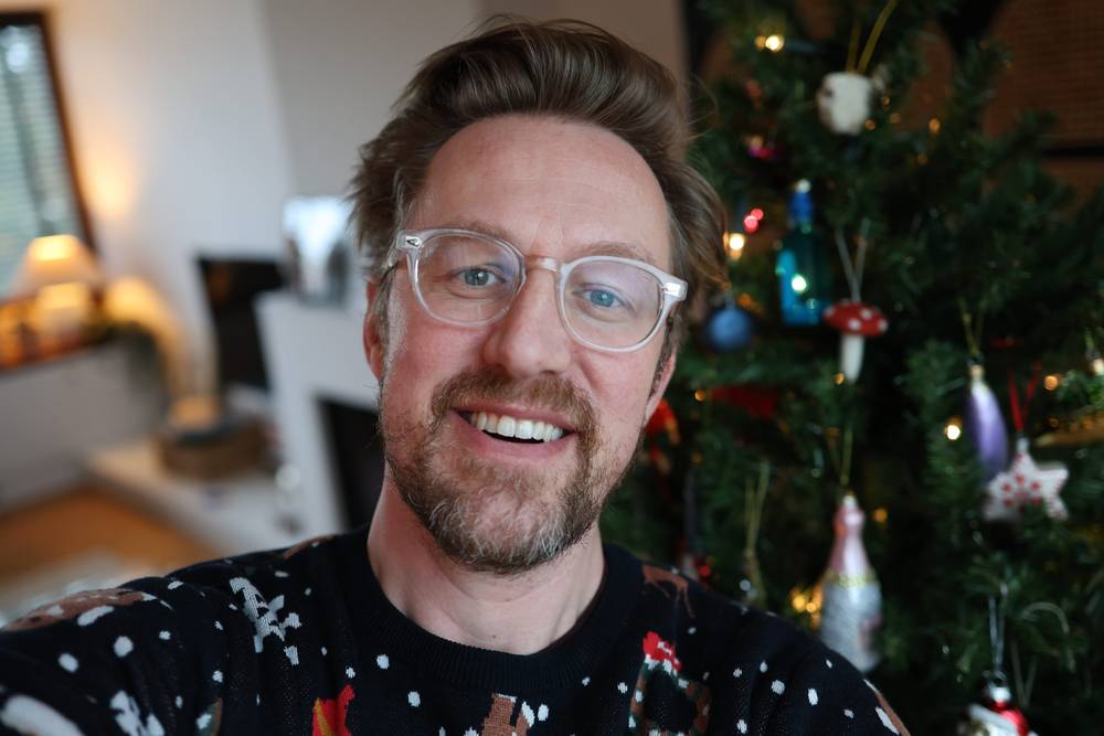 Guido in xmas sweater in front of a xmas tree