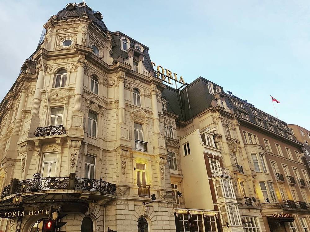 The ornate facade of the Victoria Hotel building under a clear sky.