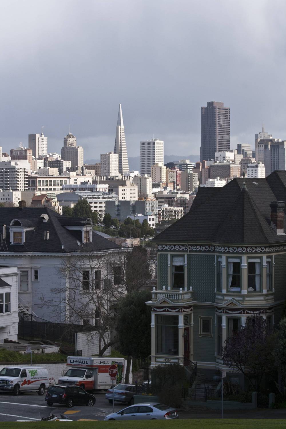 San Francisco's skyline rises above rooftops of ornate Victorian houses.