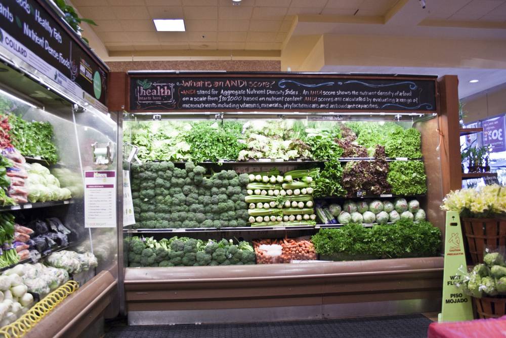 Rows of fresh broccoli, cauliflower and greens fill a grocery store produce case.