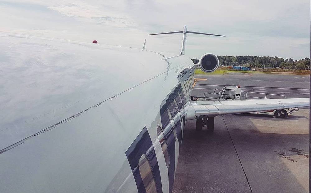 View along an airplane wing toward the runway before takeoff.