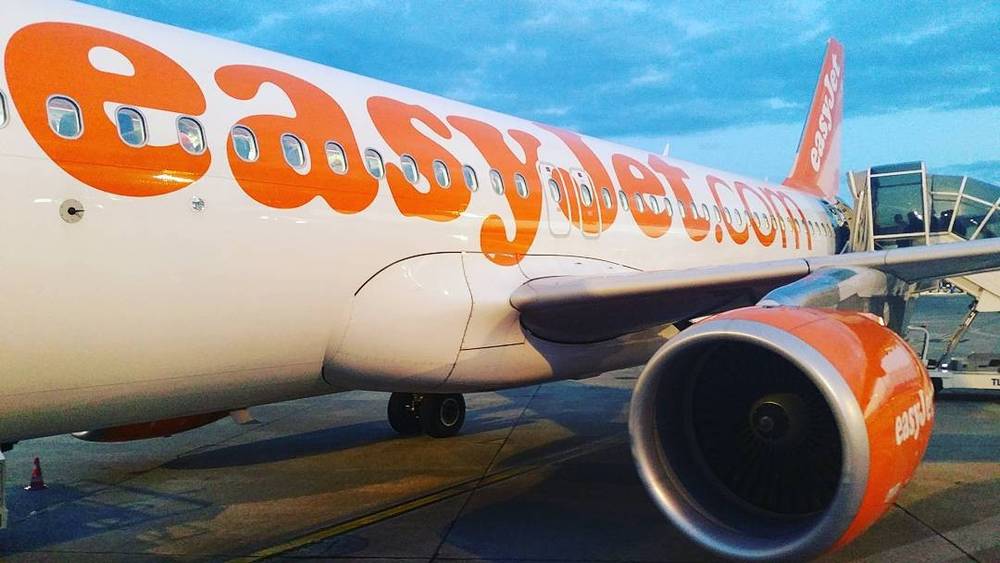 The nose and engine of an easyJet passenger plane parked at an airport.