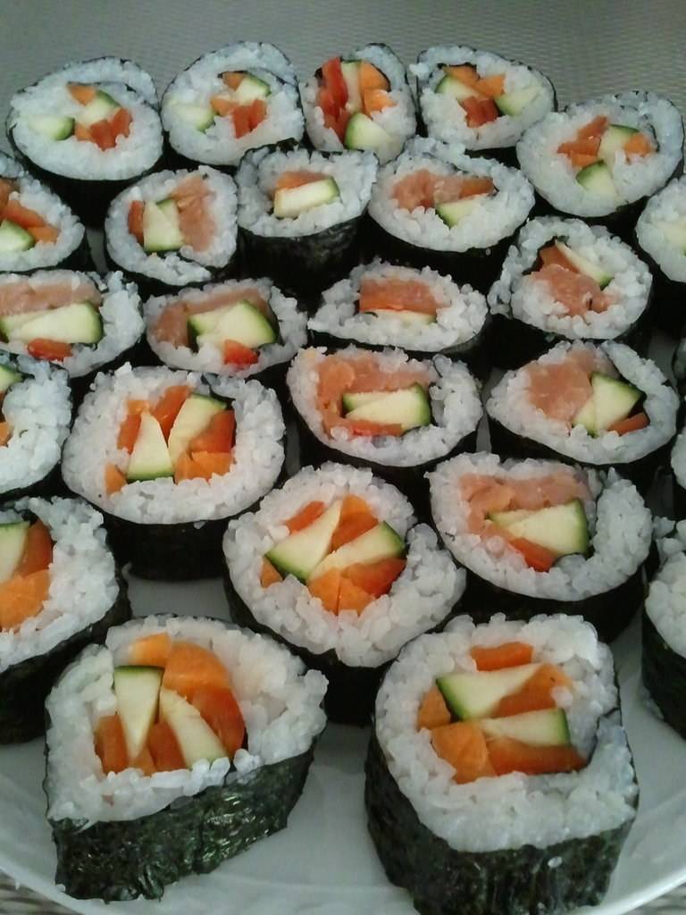 A tray of salmon and cucumber sushi rolls.