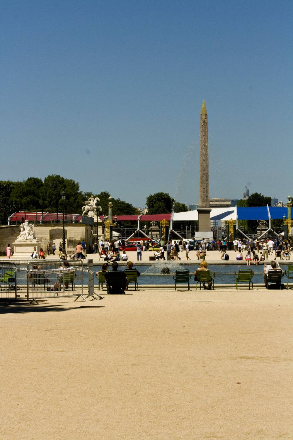 Visitors relax by the Tuileries Garden's fountain, with an obelisk visible in the distance.