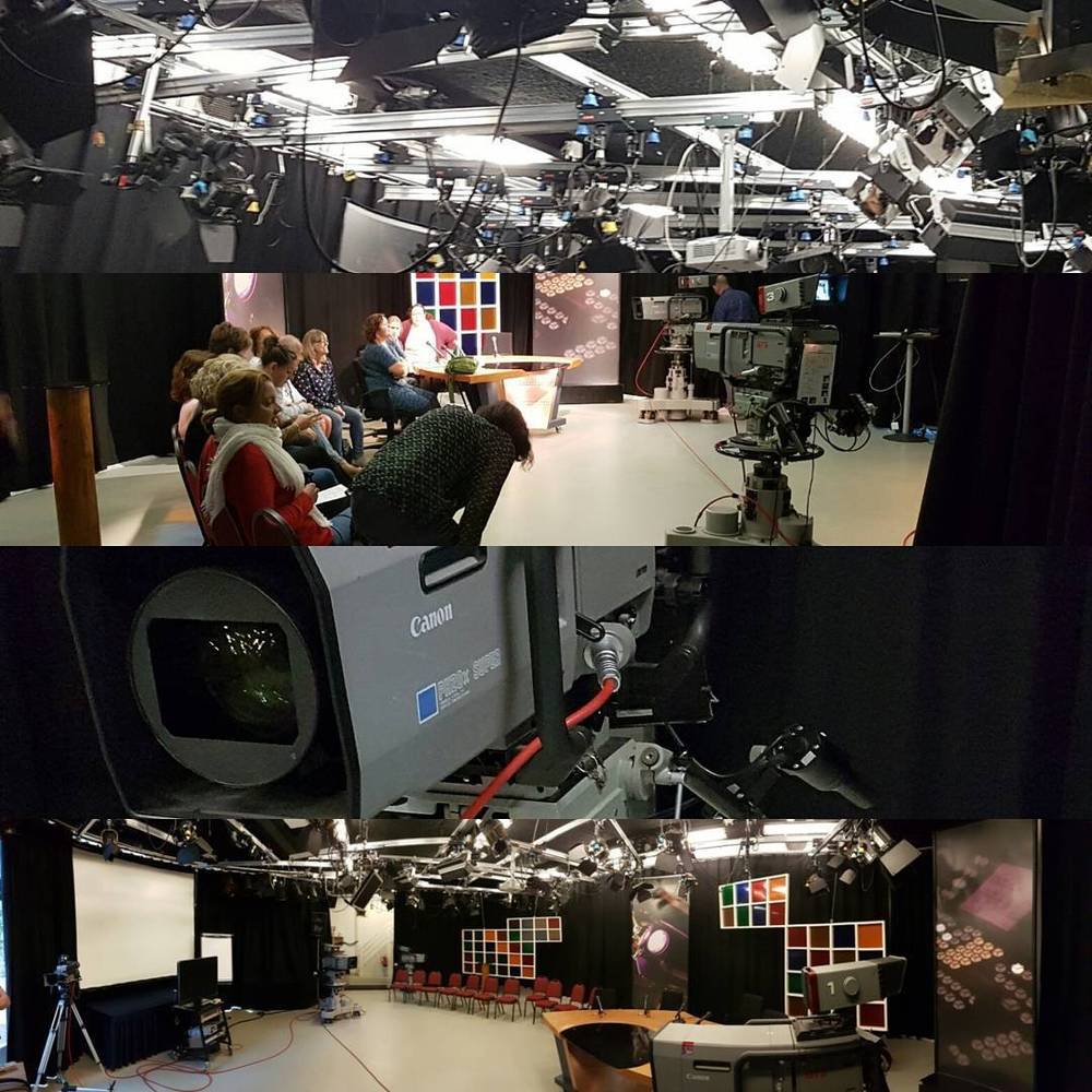 A television studio with cameras, lighting rigs, and a small seated audience.