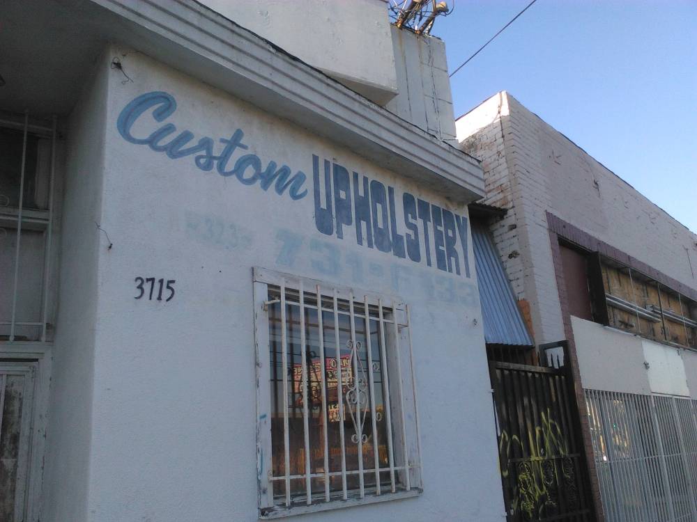 Old style letters above a window with bars, "Custom Upholstery"