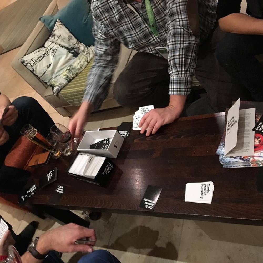 People playing a card game around a table in a cafe.