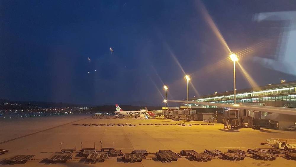 An airport tarmac at night with planes parked at illuminated gates.