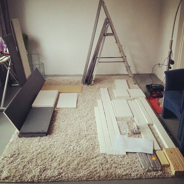Flat-pack furniture parts and tools laid out on a rug during assembly.