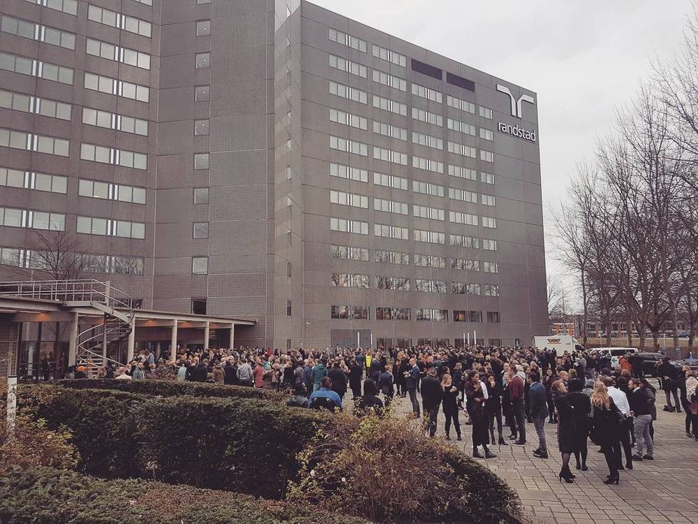 A crowd gathered outside a large office building, part of a fire drill.