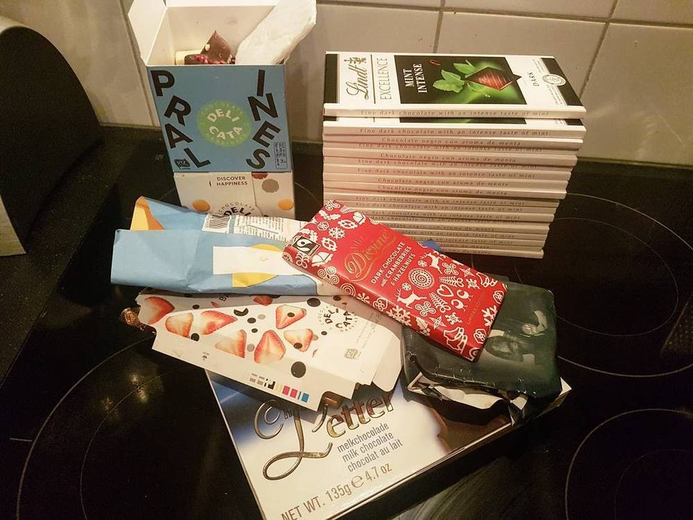 An assortment of chocolate boxes and bars stacked on a kitchen counter.