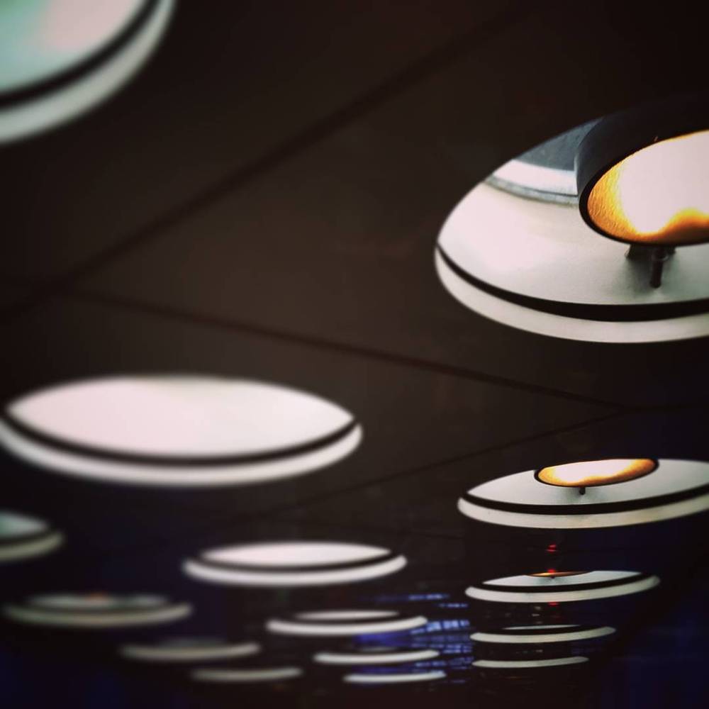 Close-up of round modern lamps or ceiling fixtures glowing in a dark room.