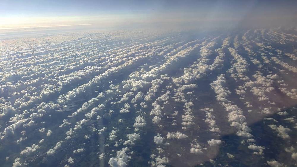 View from an airplane window over a sea of clouds at sunset.