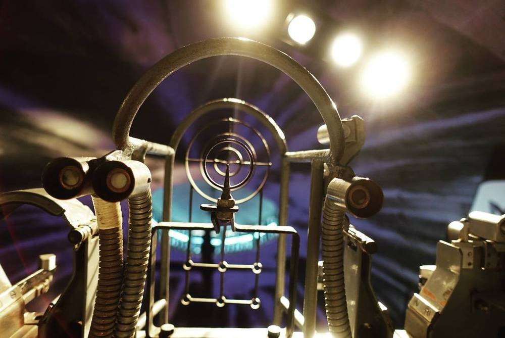 Close-up of a submarine's periscope and mechanical equipment lit dramatically from above.