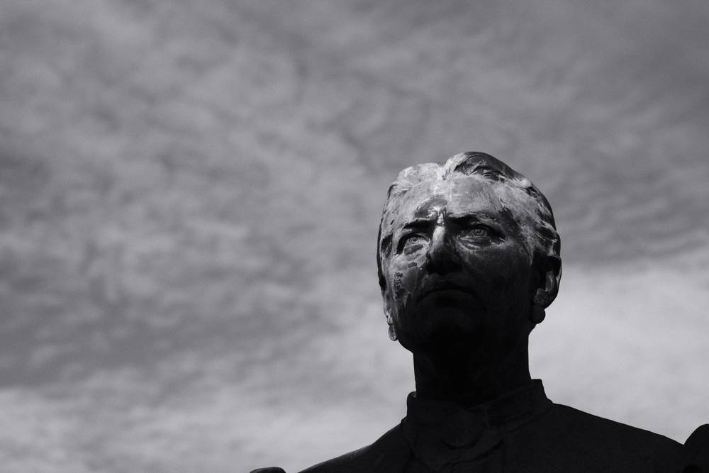 The head of a statue is partially lit by the morning sun. black and white