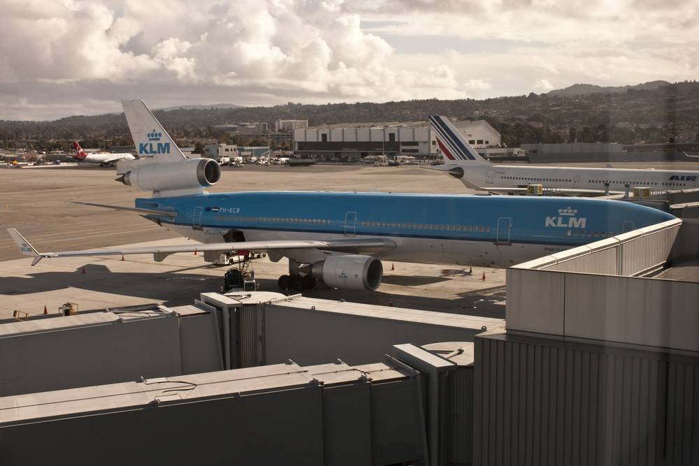 A KLM jet taxis past an Air France plane on the tarmac at an airport.