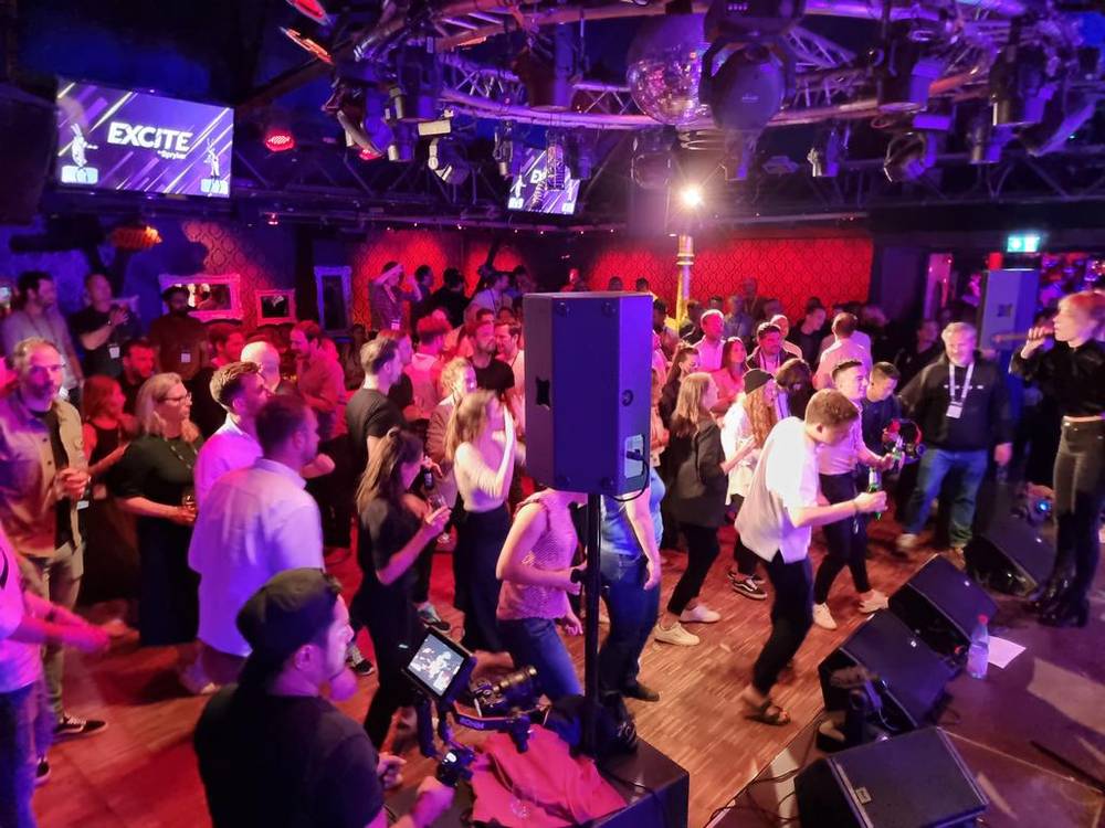 A crowd dancing under stage lights at an evening party event.